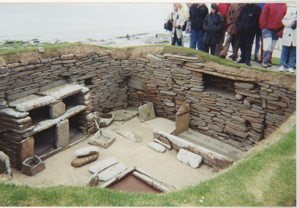 Excavated stone-built rooms at the Neolithic village of Skara Brae, with low walls and stone furnishings.